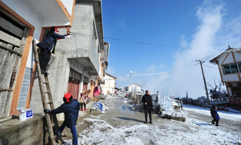 2018年1月9日，務(wù)川供電局工作人員文應(yīng)龍（左一）與同事李進(jìn)在貴州務(wù)川仡佬族苗族自治縣石朝鄉(xiāng)高峰村幫助當(dāng)?shù)卮迕窠哟罹€。（新華社記者 陶亮 攝）