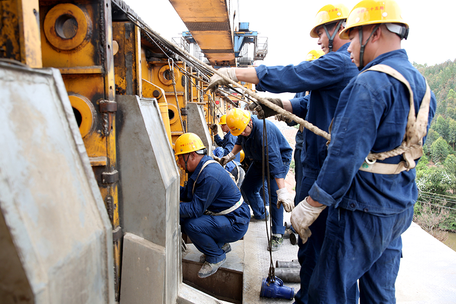 落梁吊裝過程需要40分鐘，精準(zhǔn)對位時間占了一半。裝吊工分工協(xié)作，拿著水平尺測量支座平整度，用吊錘評估支座和中心、墩臺的錯動量，用鋼尺測量四角高差……每道工序都不能少，嚴(yán)謹(jǐn)?shù)墓ぷ鲬B(tài)度才能確保每一榀箱梁精準(zhǔn)吊裝到位。圖為作業(yè)人員為架橋機過孔做準(zhǔn)備工作。（黃詩偉 攝）