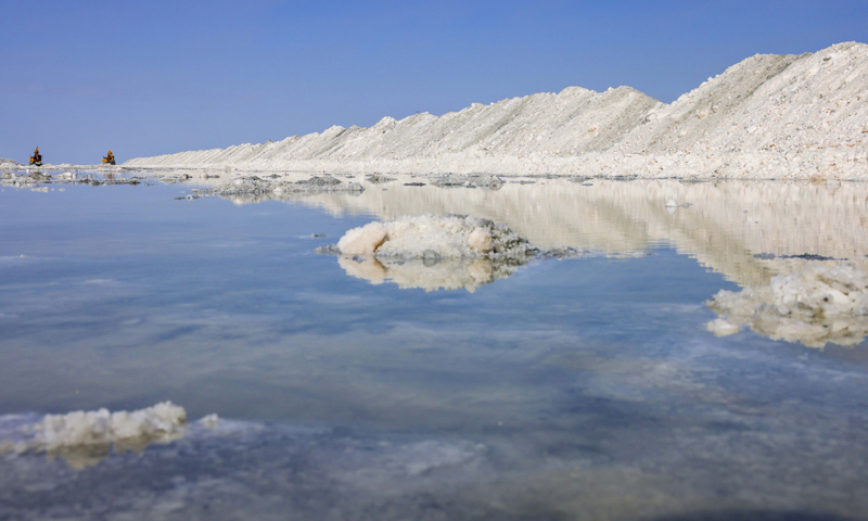 新疆和布克賽爾蒙古自治縣瑪納斯鹽湖擁有豐富的鹽礦資源，是重要的鹽業(yè)生產(chǎn)基地。近年來，當(dāng)?shù)仄髽I(yè)通過持續(xù)改進(jìn)工藝、開發(fā)特色鹽產(chǎn)品，銷售市場已從新疆拓展至國內(nèi)其他省市。圖為6月21日，中鹽宏達(dá)鹽業(yè)的工人在新疆和布克賽爾蒙古自治縣瑪納斯鹽湖中采鹽。（新華社記者 胡虎虎 攝）