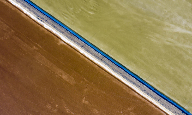 每年四月至十月是瑪納斯鹽湖的采鹽旺季，湖區(qū)內(nèi)機(jī)器轟鳴、車輛穿梭，一片繁忙景象。圖為6月21日，在新疆和布克賽爾蒙古自治縣瑪納斯鹽湖中鹽宏達(dá)鹽業(yè)生產(chǎn)基地拍攝的一處灘曬池。（新華社記者 胡虎虎 攝）