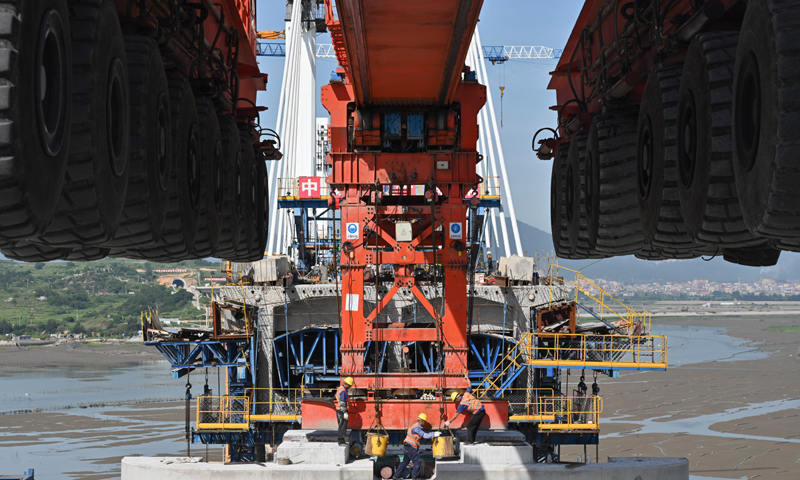圖為7月11日，在新建福廈鐵路湄洲灣跨海大橋建設(shè)現(xiàn)場，中鐵十一局工人協(xié)同“昆侖號”千噸級運架一體機架設(shè)該線路最后一孔40米箱梁。（新華社記者 宋為偉 攝）