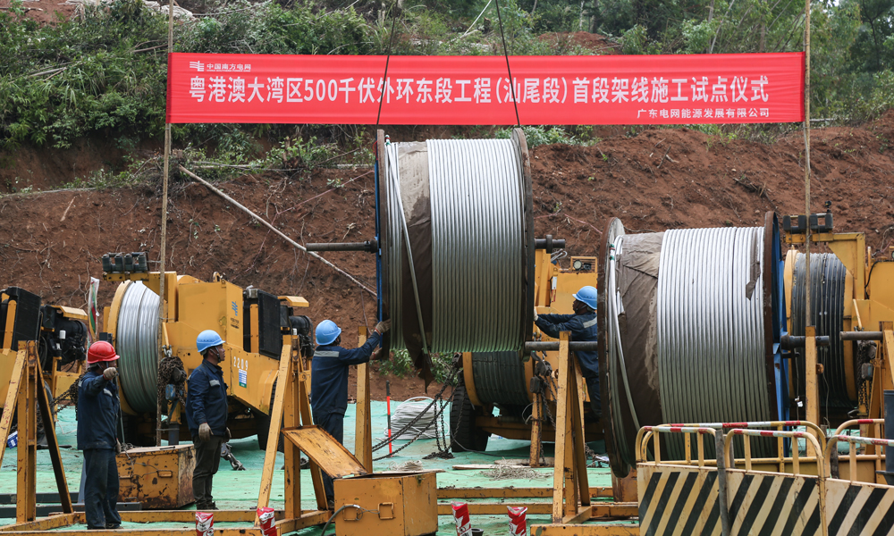 該工程對保障粵港澳大灣區(qū)電力能源安全、支撐新型能源體系建設(shè)、服務(wù)大灣區(qū)高質(zhì)量發(fā)展具有重要意義。圖為工作人員在張力場進(jìn)行導(dǎo)線盤起吊，為導(dǎo)線展放做好準(zhǔn)備。