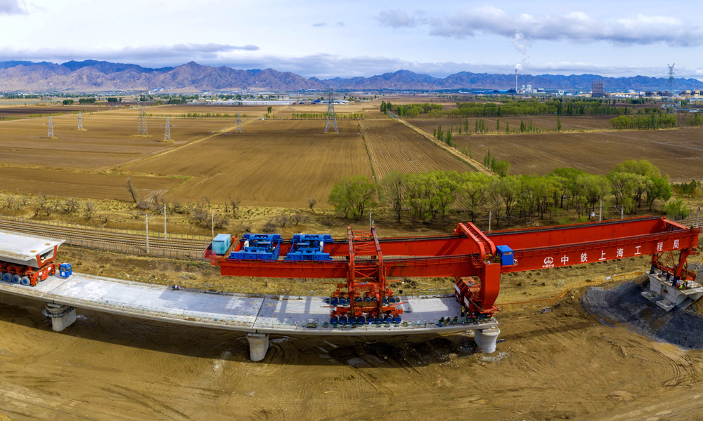 近日，中國中鐵旗下中鐵上海局承建的包（頭）銀（川）高鐵跨萬甘鐵路特大橋完成箱梁架設，標志著包銀高鐵內蒙古段首座跨鐵路特大橋主體工程全部結束。圖為包銀高鐵跨萬甘鐵路特大橋箱梁架設施工現場。