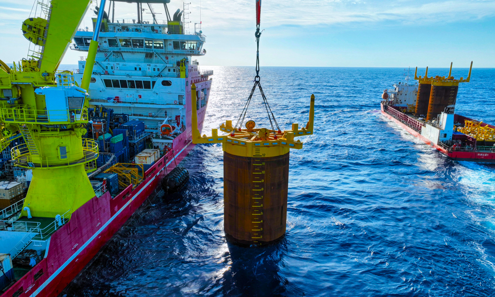 項目部根據吸力樁重心位置量身定制3套吊裝索具，確保起吊時樁體垂直于海平面。現場強化定位精度控制，布控6個定位信標，形成“六邊形”定位陣校準方陣。投入兩臺ROV（水下機器人），采用“阻尼艏向調整法”進行艏向細微調整，保證艏向精度。貫入作業中，船舶吊機和ROV協同作業，精準控制鉤頭載荷和貫入壓力，確保吸力樁緩慢平穩沉降。最終實現了3套吸力樁一次性高精度貫入成功。圖為吸力樁安裝作業現場。