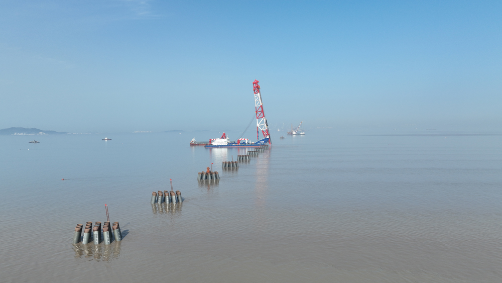 近日，由中交集團所屬二航局投資打造的全球最大打樁船“二航長青”亮相東海，將一根長98.5米的鋼管樁精準釘入海底巖層，助力杭州灣跨海鐵路大橋步入建設快車道。