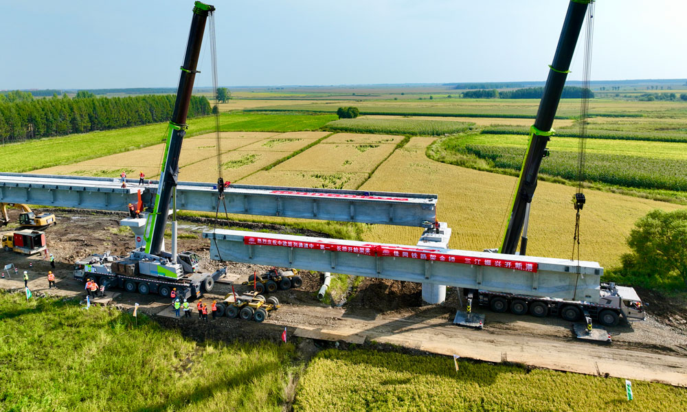 此次進入架梁階段的佳木同江特大橋位于同江至同江北改建段，是全線控制性工程，橋梁全長10435.14米，采用單線T梁結(jié)構(gòu)設(shè)計，是我國目前中歐班列三大通道中口岸段最長新建橋梁。圖為架橋機在架設(shè)梁體。