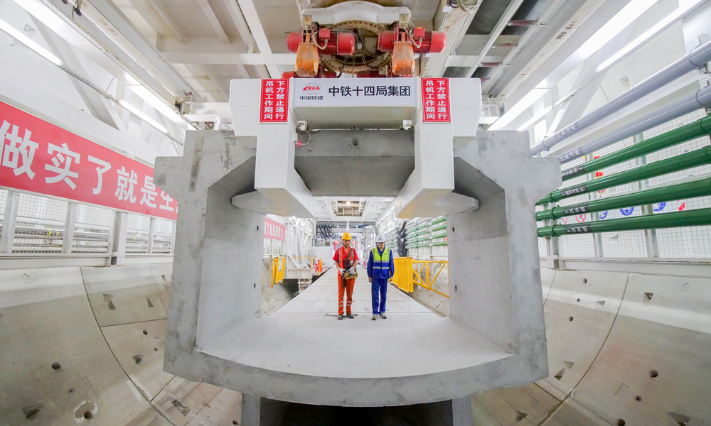 日前，中國鐵建重點項目搶抓施工黃金期，迅速掀起大干熱潮。圖為3月13日，在重慶市南岸區南山下140多米深處，中鐵十四局承建的重黔鐵路長江隧道建設者在隧道內拼裝箱涵。