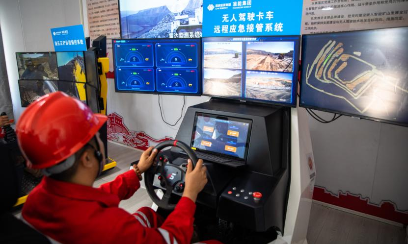 在準(zhǔn)能集團黑岱溝露天煤礦智能礦山建設(shè)現(xiàn)場指揮中心，技術(shù)員正在通過無人駕駛卡車遠程應(yīng)急接管系統(tǒng)實時監(jiān)控行車路線。該設(shè)備用于對無人駕駛卡車監(jiān)控和遠程應(yīng)急接管，可有效保障無人駕駛運輸系統(tǒng)的持續(xù)作業(yè)，為無人駕駛安全提供保障。該礦運用多編組車輛智能化調(diào)度與管理系統(tǒng)，實現(xiàn)三編組無人駕駛卡車同時運行和多車智能協(xié)同裝卸，大幅提升了無人作業(yè)效率。包文學(xué) 攝