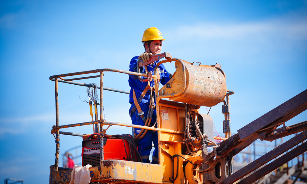 在陸地，建設人員倒排工期快施工，實現了原油處理站、生產水處理站、天然氣液化站、石油氣液化站、變電站、5G基站“六站合一”。其中，生產水處理站采用四級工藝處理生產水，處理后純凈度高。變電站將綠色岸電變壓后輸至海上平臺，替代傳統的燃氣發電，減碳效果突出。5G網絡“連通”海上，為無人機巡檢海上設施、海面24小時溢油苗頭監測等各種智能應用鋪筑了“信息傳輸高速路”。圖為施工人員準備登高作業。