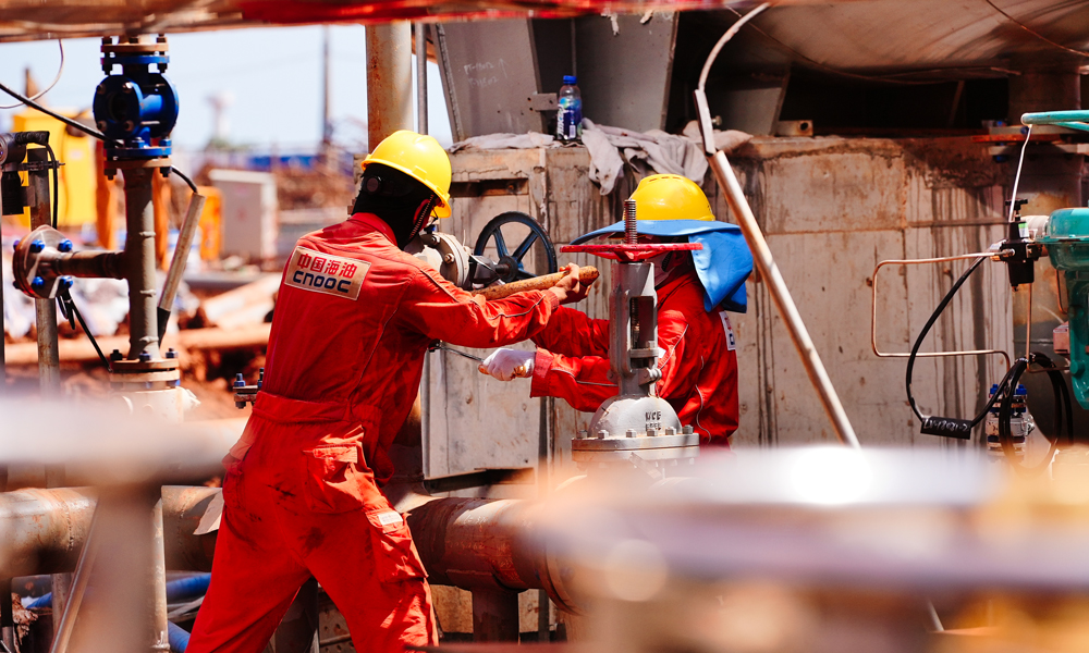 在海上，千人劈波斬浪施工忙。今年3月先后完成兩個平臺的安裝，隨后爭分奪秒鉆井——鉆井人員優化井身結構、研用高性能環保鉆井液，破解了斷塊地層鉆進易坍塌、致密薄儲層難鉆遇的難題。今年5月，首批6口井完鉆，較計劃提前40天。同時，海上配備的固定式圍油欄筑牢安全環保堅實防線。圖為現場施工人員在安裝閥門。