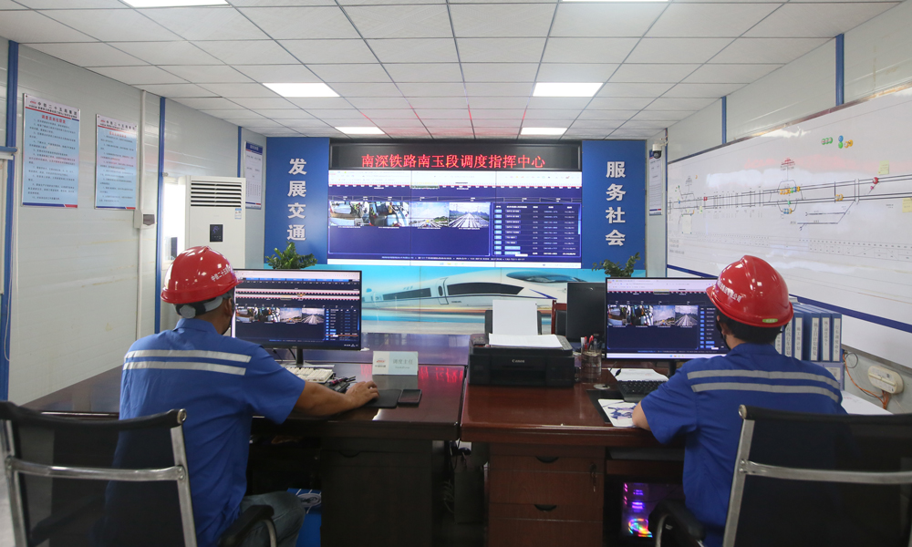 南深高鐵南玉段項目沿線地形地貌復雜，橋隧比達83.8%，長鋼軌運輸和鋪設多次跨越既有鐵路、公路、航道，施工安全風險高。針對上跨南寧動車所、湘桂線、黎湛線、黎欽線，臨近南廣線、云欽聯絡線等既有鐵路高風險施工段，中鐵二十五局建設團隊啟用調度指揮中心，實現沿線鋪軌作業的智能化、專業化、信息化，大幅提升了安全管理水平和鋪設質量。圖為建設者在調度指揮中心監測鋪軌施工情況。