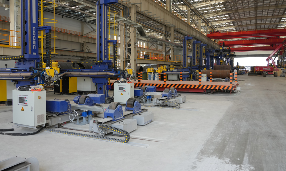 在海油工程天津智能制造基地二期項目的結構管線智造車間，一臺巨大的起重機正進行調試作業，不遠處焊花四濺，工人們正用焊槍進行設備組裝固定。據介紹，該智造車間面積超1.1萬平方米，生產線采用先進的智能技術，可實現智能化決策支持、自動化生產和標準化作業。圖為海油工程臨港智能制造基地二期工程車間。