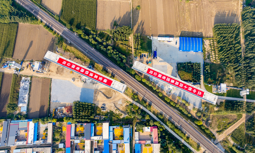 據介紹，任丘特大橋跨京九鐵路轉體橋是項目關鍵控制性工程，為雙幅結構，單邊橋體長126米，橋面寬12.6米，重1.01萬噸，橋梁距離鐵路防護柵欄最小距離為9.5米，轉體后距鐵路接觸網垂直距離僅2.9米。施工過程中，對主梁線形控制、技術精度要求極高，安全風險較大。圖為任丘特大橋跨京九鐵路轉體橋正在轉體中航拍。