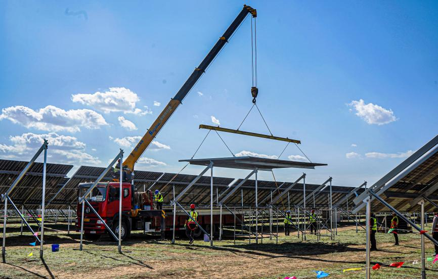 該項目創新“一體化支架+組件施工”技術，這在國際上是首次應用，大大減少了人工作業，提高安裝效率達25%。當前，項目組件安裝超過90%，國電電力內蒙古綜合能源工作人員全力以赴保障工程建設進度，沖刺10月底并網發電目標。圖為10月15日，吊車將組裝好的一體化模塊吊裝在支架上。