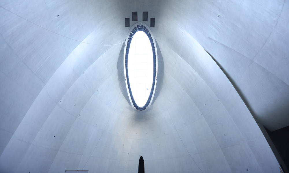 異形曲面清水混凝土、異形曲面石材幕墻、曲面薄殼結構等在塑造建筑特色的同時，也為施工建造帶來巨大挑戰。大體量異形曲面清水混凝土施工及異形曲面石材幕墻施工在國內和國際上均鮮有類似案例。其中最具代表性的清水混凝土結構整體為相互交錯且無明確邊界的瑪雅無規則曲面造型，施工難度國內罕見。清水混凝土展開面積達3萬平方米。圖為項目攝云石四層29米超高展廳清水混凝土施工成品效果。