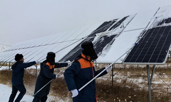 中廣核山西右玉風光互補電站作業人員清除電站周邊通道及光伏板上的積雪。