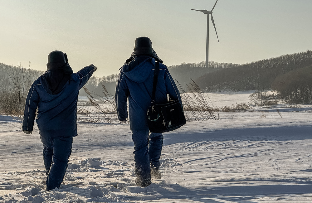 中廣核黑龍江興凱湖風電場接獲天氣預警后，即刻啟動集電線路與風機葉片覆冰應急處置方案，組建“葉片檢查突擊隊”借助無人機檢查葉片覆冰情況，“道路搶修突擊隊”聯合道路維護隊清理檢修道路急彎陡坡積雪，并撒防滑料以保暢通，同時暫停風機檢修防落冰傷人。