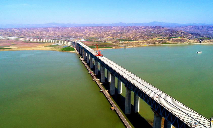 三門峽黃河公鐵兩用大橋主橋?yàn)橄聦铀木€鐵路與上層六車道高速公路結(jié)構(gòu)。上層公路橋面系采用先張法預(yù)應(yīng)力混凝土橋面板，橋面板與公路橫梁及上弦桿上布置的剪力釘通過濕接縫澆筑結(jié)合成整體。圖為三門峽黃河公鐵兩用大橋公路橋面板架設(shè)遠(yuǎn)景。
