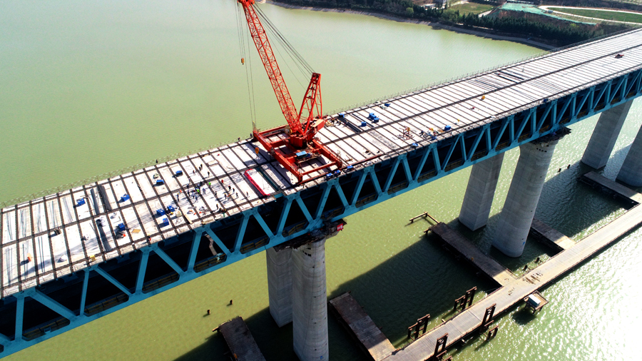 為克服高空作業(yè)、橋面板運(yùn)輸困難、起吊噸位大、施工周期長等不利因素，施工團(tuán)隊(duì)多次召開技術(shù)培訓(xùn)交底會，在鋼桁梁南北兩端分別配備一臺70噸全回轉(zhuǎn)吊機(jī)進(jìn)行架設(shè)施工，安排專人進(jìn)行現(xiàn)場實(shí)時(shí)監(jiān)管，確保安全、質(zhì)量、進(jìn)度全面可控。圖為三門峽黃河公鐵兩用大橋公路橋面板架設(shè)遠(yuǎn)景。