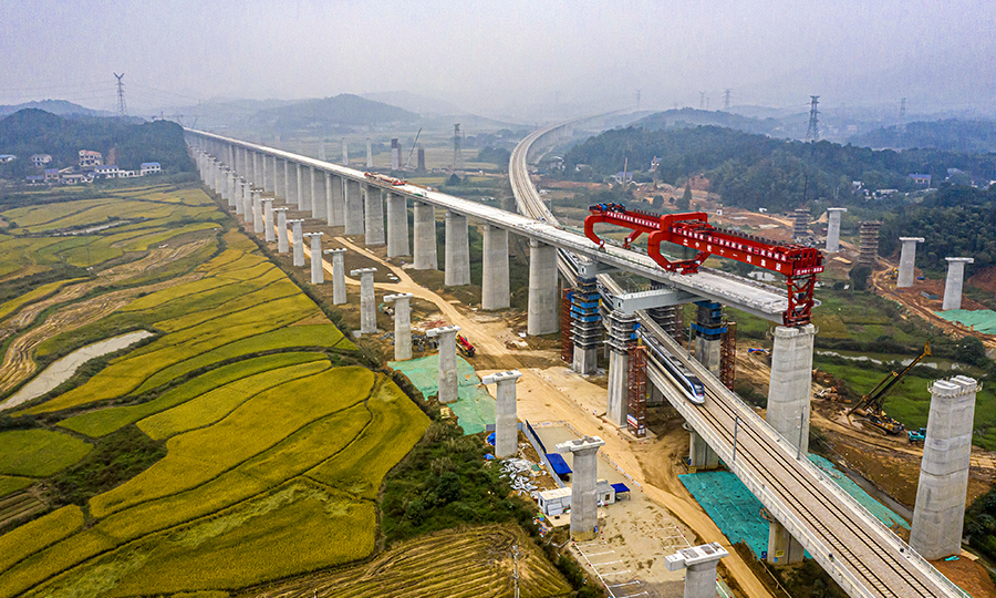 為保證施工順利進行，該項目部經(jīng)過方案比選，采用了“門式墩鋼蓋梁+簡支箱梁”的形式跨越，大大降低了安全風險，有效縮短了施工周期，并降低了施工成本。圖為10月13日，一列動車從架梁施工現(xiàn)場通過。（彭特 攝）